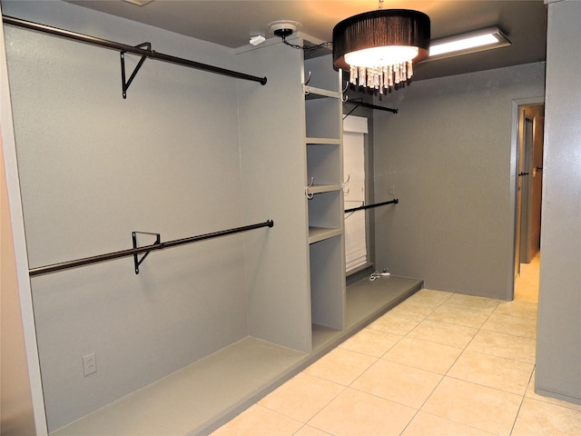 spacious closet featuring light tile patterned floors and an inviting chandelier