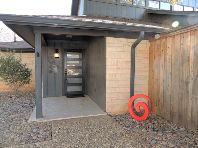 doorway to property with roof with shingles