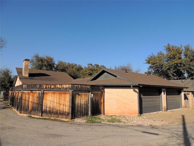 view of front of property with fence, roof with shingles, and a chimney