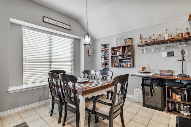 dining room featuring light tile patterned floors, a dry bar, baseboards, and lofted ceiling