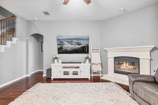 2604 Leisure Ln, Little Elm, TX 75068 - living room with dark wood-type flooring, a ceiling fan, stairs, a glass covered fireplace, and arched walkways