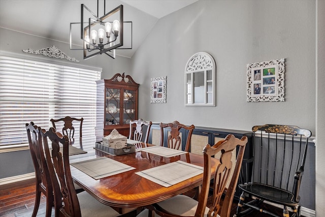 dining space featuring baseboards, wood finished floors, an inviting chandelier, and vaulted ceiling