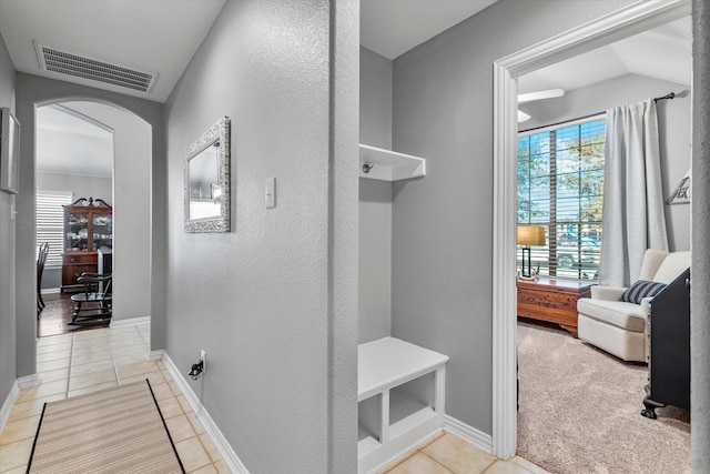 hall featuring arched walkways, visible vents, baseboards, and light tile patterned floors