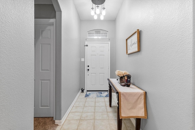 doorway featuring baseboards, arched walkways, and light tile patterned flooring