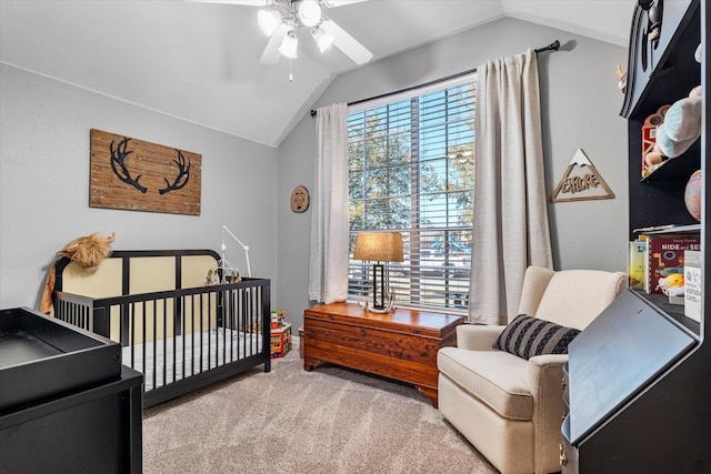 carpeted bedroom featuring a crib, lofted ceiling, and a ceiling fan