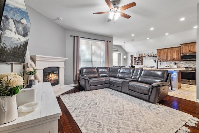 living room featuring light wood finished floors, lofted ceiling, recessed lighting, a high end fireplace, and ceiling fan