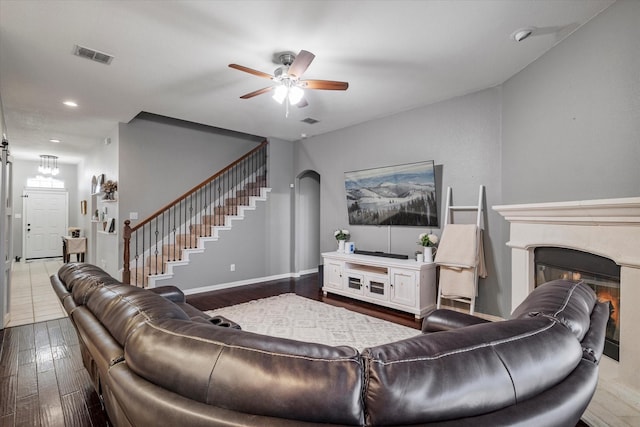 living area with wood finished floors, visible vents, ceiling fan, stairs, and a glass covered fireplace