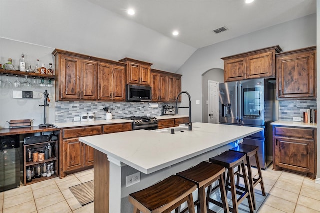 kitchen with visible vents, a sink, arched walkways, appliances with stainless steel finishes, and light tile patterned floors