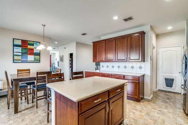 kitchen with hanging light fixtures, visible vents, backsplash, and light countertops