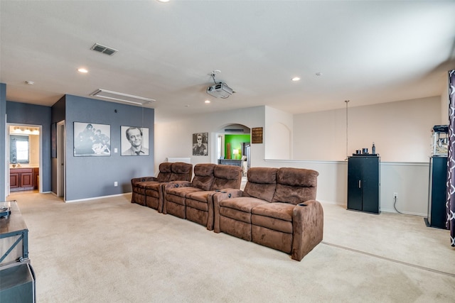 living room featuring visible vents, recessed lighting, arched walkways, light colored carpet, and attic access