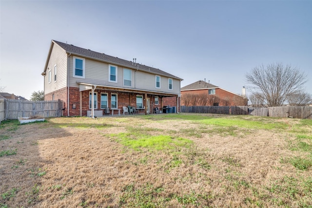 back of property featuring brick siding, a yard, and a fenced backyard