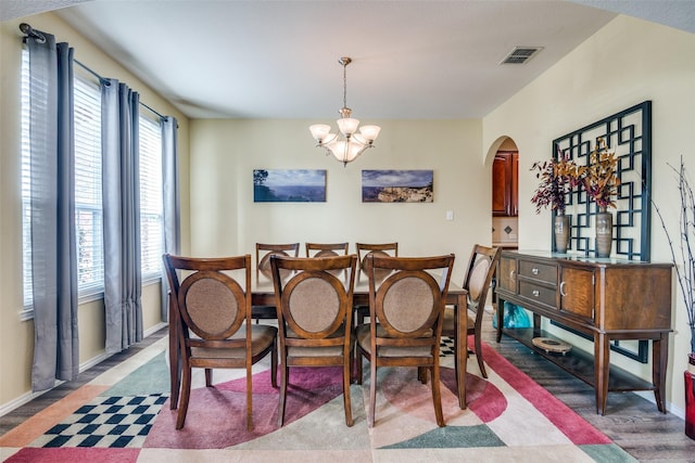 dining room featuring baseboards, arched walkways, visible vents, and a chandelier