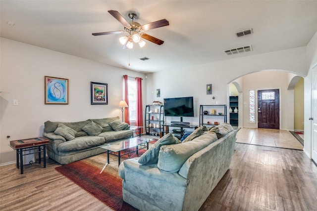 living area featuring arched walkways, visible vents, and wood finished floors