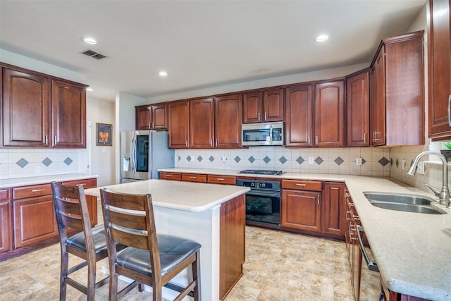 kitchen with a sink, appliances with stainless steel finishes, a kitchen bar, tasteful backsplash, and a center island