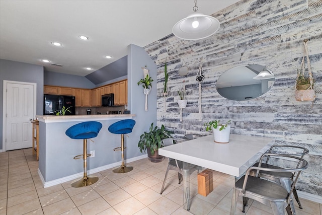 kitchen with a breakfast bar, black appliances, light tile patterned floors, and light countertops