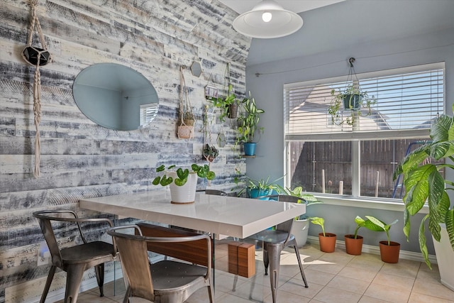 tiled dining room featuring baseboards and an accent wall