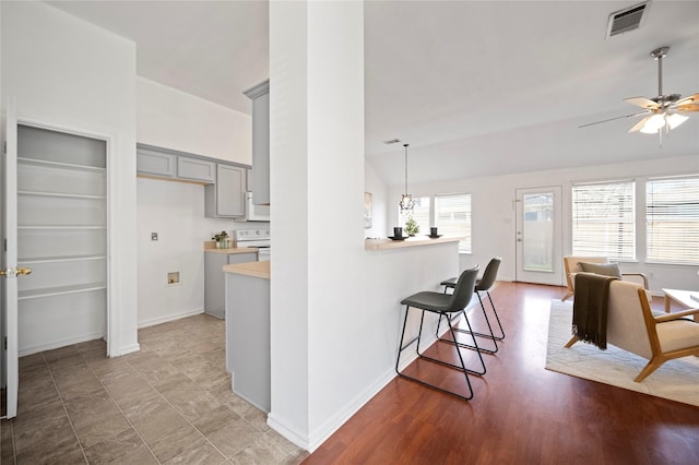 kitchen with a breakfast bar area, visible vents, lofted ceiling, gray cabinetry, and light countertops