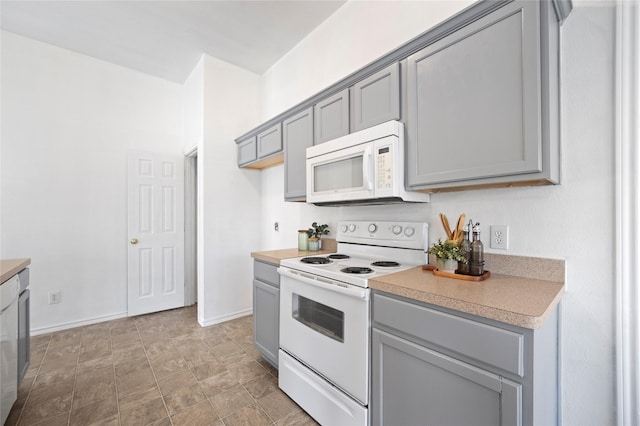 kitchen with gray cabinets, white appliances, light countertops, and baseboards