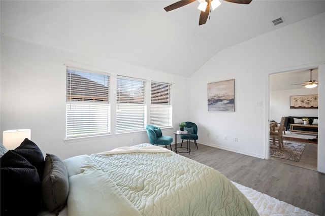 bedroom featuring visible vents, a ceiling fan, wood finished floors, baseboards, and vaulted ceiling