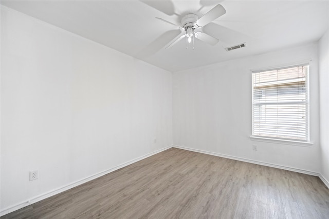 empty room with visible vents, baseboards, wood finished floors, and a ceiling fan