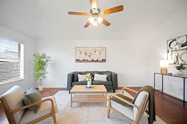 living area with a ceiling fan, vaulted ceiling, wood finished floors, and baseboards