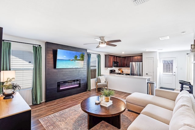 living area featuring visible vents, a large fireplace, ceiling fan, recessed lighting, and wood finished floors