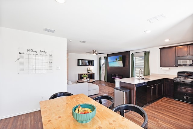 kitchen with visible vents, a sink, wood finished floors, gas stove, and a peninsula