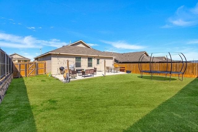 rear view of property with a fenced backyard, a lawn, a patio, and a trampoline