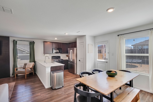 kitchen featuring visible vents, a sink, light wood-style floors, black microwave, and high end refrigerator