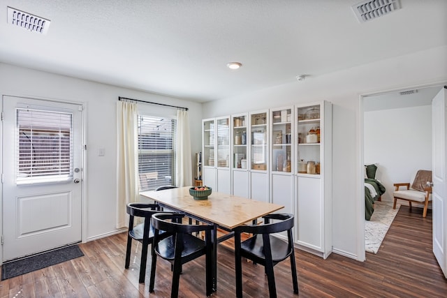 dining room featuring visible vents and dark wood-style flooring