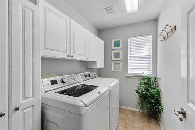 clothes washing area with cabinet space, visible vents, washing machine and dryer, and baseboards