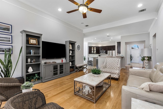 living area featuring visible vents, crown molding, recessed lighting, light wood-style floors, and a ceiling fan