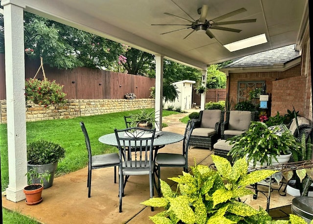 view of patio / terrace with ceiling fan, a storage shed, a fenced backyard, an outdoor structure, and outdoor dining space