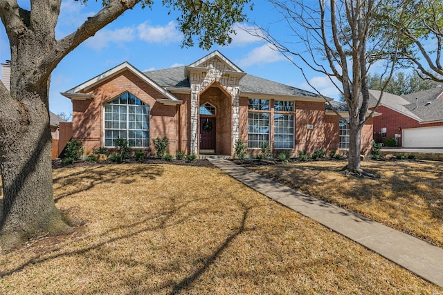 view of front of property with brick siding, stone siding, a shingled roof, and a front yard