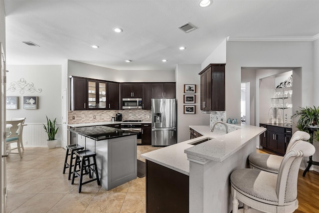 kitchen featuring a breakfast bar, visible vents, stainless steel appliances, and a sink