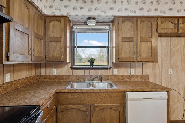 kitchen with a sink, wall chimney exhaust hood, brown cabinetry, and white dishwasher