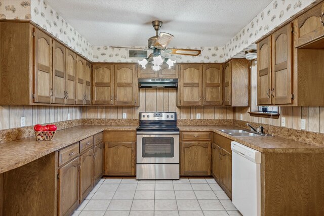 kitchen featuring wallpapered walls, under cabinet range hood, dishwasher, stainless steel range with electric cooktop, and a sink