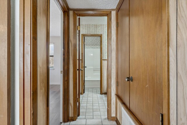 unfurnished room featuring wood finished floors, baseboards, ceiling fan, a textured ceiling, and a textured wall