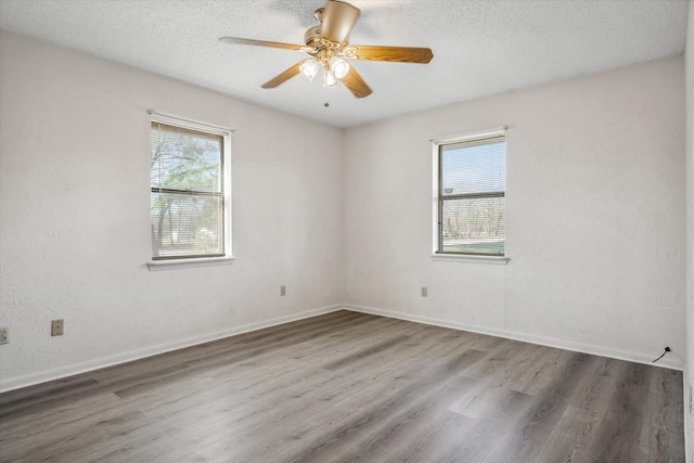 empty room with wood finished floors, baseboards, and a textured ceiling