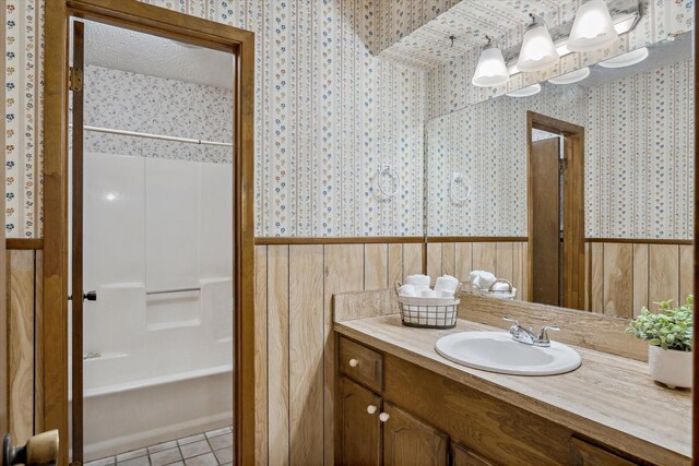 bathroom featuring vanity, shower / washtub combination, tile patterned flooring, and wallpapered walls