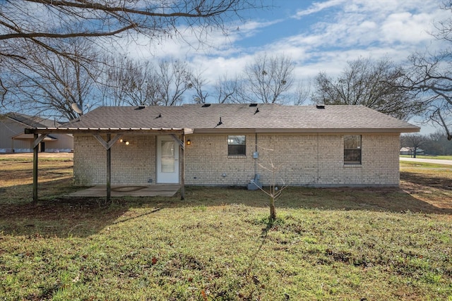 rear view of property featuring a patio area, brick siding, a yard, and a shingled roof