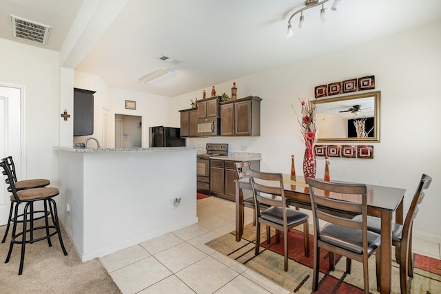 kitchen featuring dark brown cabinets, visible vents, black appliances, and light tile patterned flooring