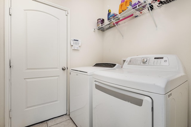 washroom featuring washer and dryer, light tile patterned flooring, and laundry area