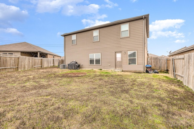 rear view of property with a fenced backyard, central AC unit, and a yard