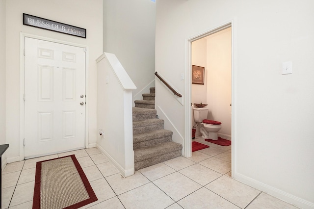 foyer entrance featuring light tile patterned floors, baseboards, and stairs