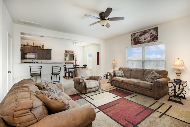 living area with visible vents, light colored carpet, and ceiling fan