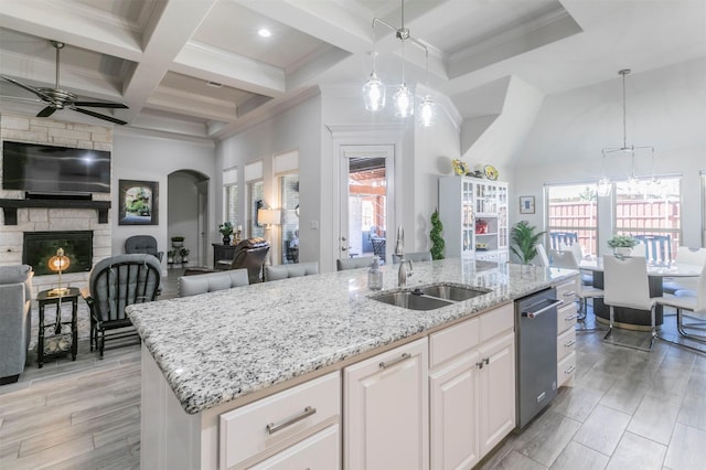 kitchen featuring a kitchen island with sink, a sink, coffered ceiling, open floor plan, and a fireplace