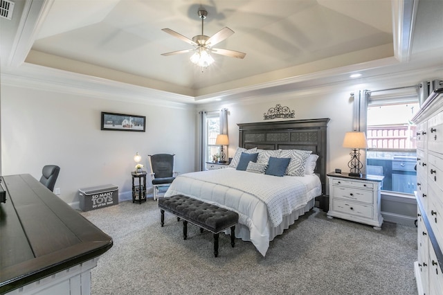 bedroom featuring visible vents, a tray ceiling, carpet, crown molding, and baseboards