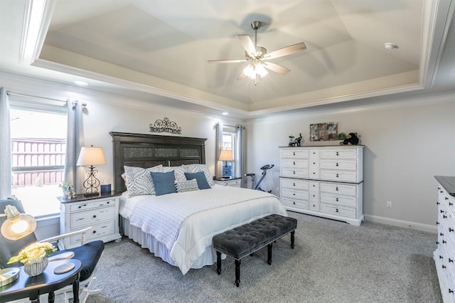 carpeted bedroom featuring baseboards, a raised ceiling, a ceiling fan, and crown molding