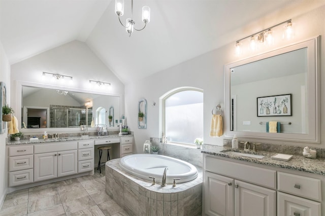 full bath featuring two vanities, lofted ceiling, a bath, and a sink